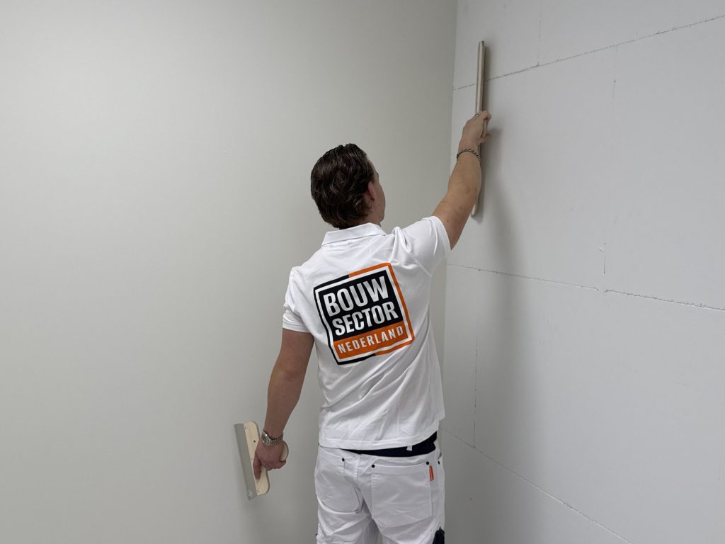 Vakman van Bouwsector Nederland controleert met een rei of de wand vlak genoeg is